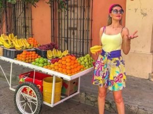 Turistas disfrutando de un colorido puesto de frutas en un tour por la ciudad de Cartagena, resaltando la vibrante atmósfera urbana.