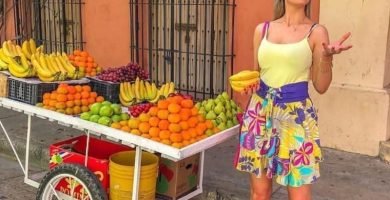 Turistas disfrutando de un colorido puesto de frutas en un tour por la ciudad de Cartagena, resaltando la vibrante atmósfera urbana.